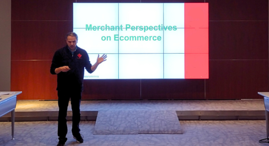 Instructor in front of screen describing merchant perspectives in e-commerce.